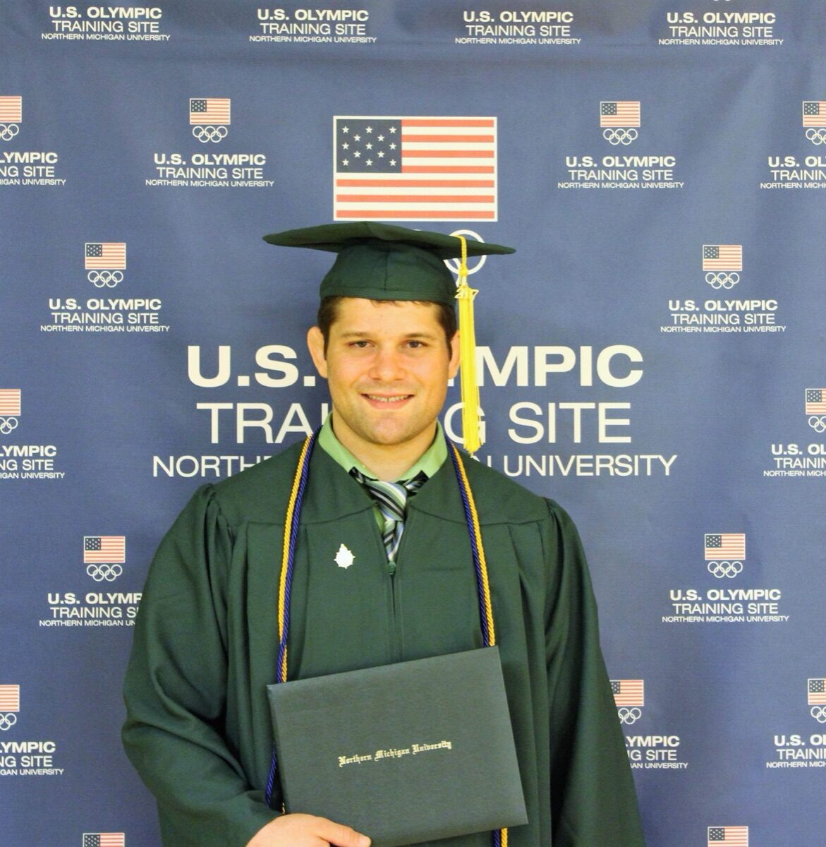 Orry Elor at his Northern Michigan University graduation, in front of the U.S. Olympic Training Site backdrop